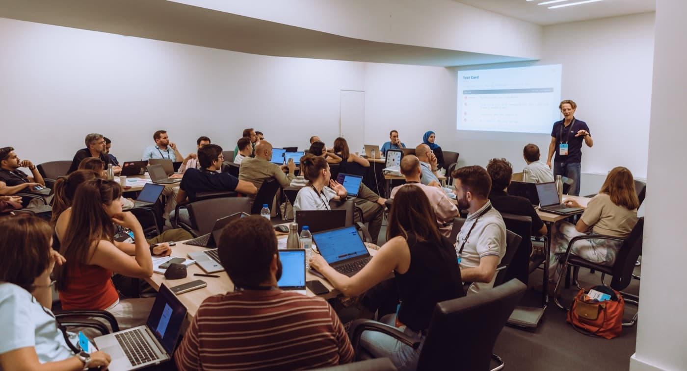 A full workshop room of product people working while a facilitator presents